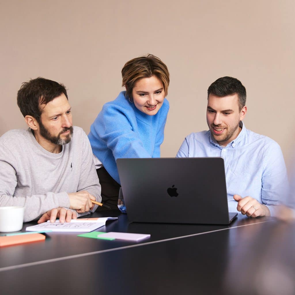 Matthias, Carola und Richard arbeiten im Team an einem Laptop